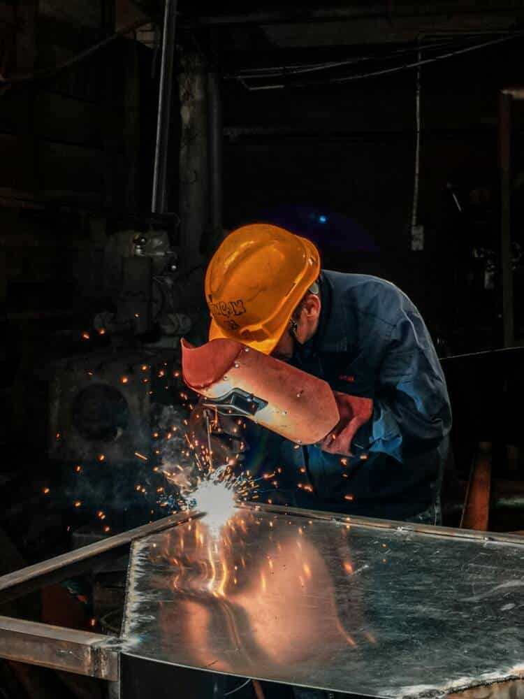 Depiction of a metalworker welding in a workshop with protections