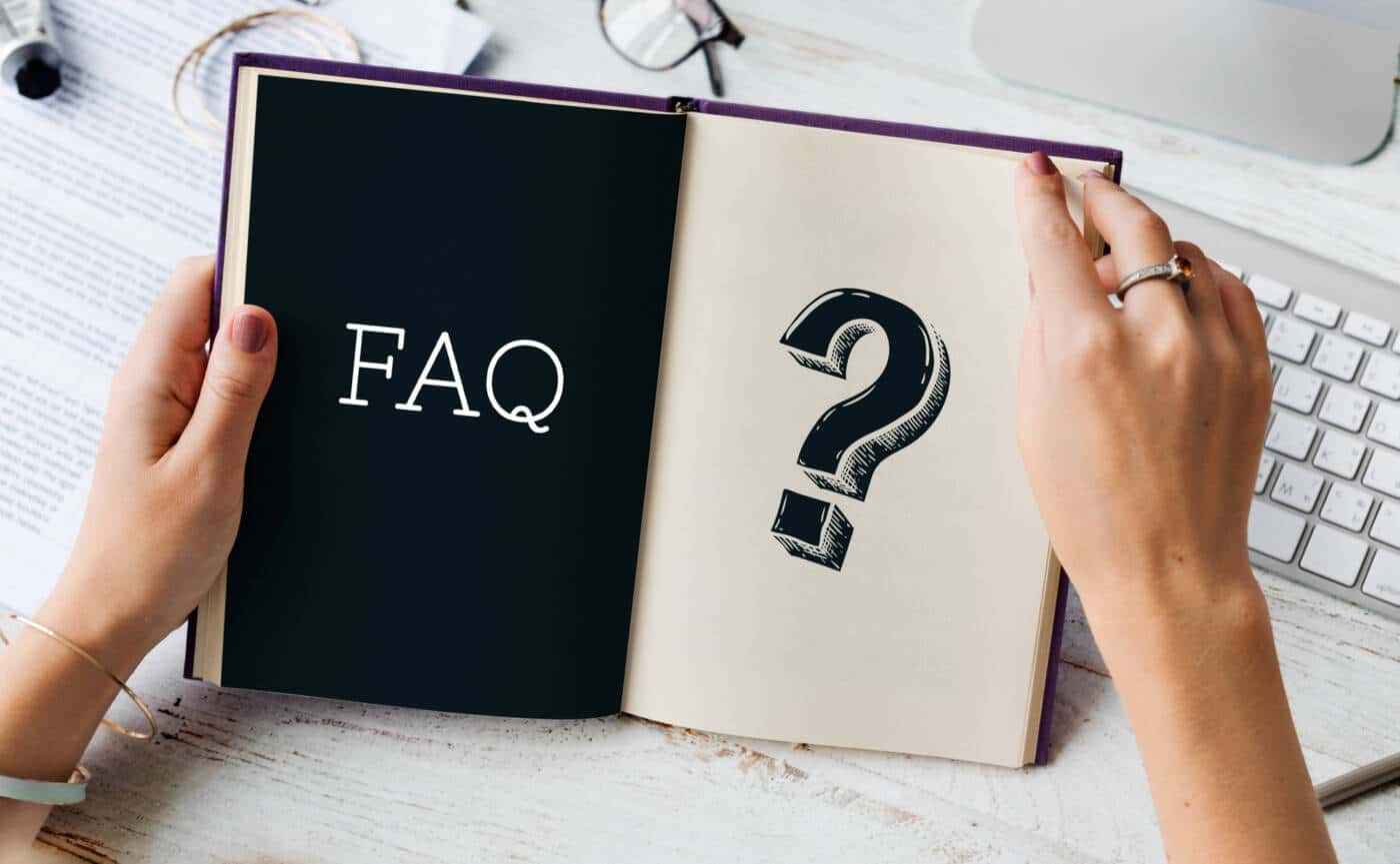 Book held in hands with a question mark and the words "Q&A" on a desk background with several objects on it